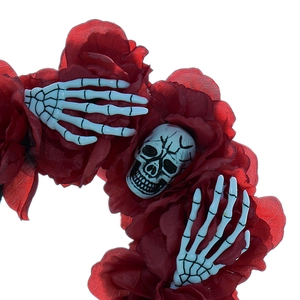 Close-up of Halloween headband with red roses and white skull hands on a white background