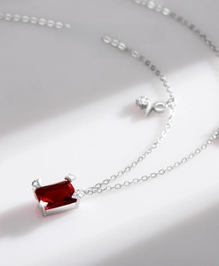 Macro view of rectangular red zircon pendant with diamond accents on silver chain