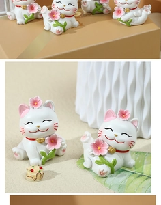 Close-up of cute white resin lucky cat figurines with pink cherry blossoms and gold bells