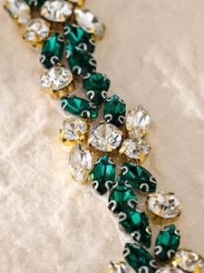 Macro shot of emerald crystals and diamonds on luxury bridal gown sash with gold base