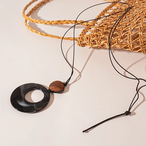 Detail of resin geometric pendant necklace with wood beads on minimalist cord