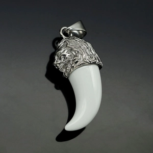 Close-up of a stainless steel lion head pendant with a white resin fang on a dark surface