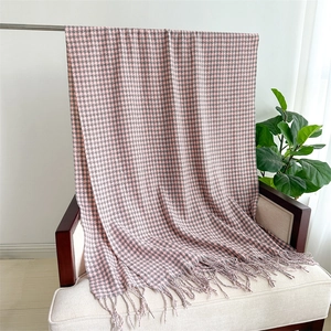 Detailed view of pink and grey houndstooth knit scarf with tassels hanging on a chair