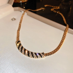Macro detail of gold snake chain with black enamel stripes and diamond inlay