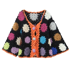 Macro detail of handmade crochet cardigan showing colorful floral knit and orange trim