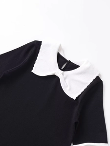 Detailed close-up of a black knit T-shirt featuring a white Peter Pan collar and trim