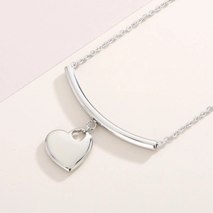 Close-up of a silver stainless steel smile bar and heart pendant necklace set