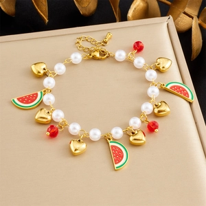 Detail of beaded bracelet with pearl chain, gold heart and watermelon enamel charms