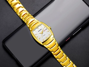 Detailopname van goudkleurig tonneau horloge met dag-datum op een donkere basis