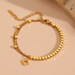 Close-up of double-layered gold titanium steel bracelet with clover and square charms