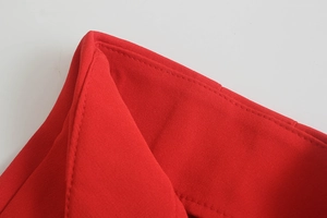 Dettaglio ravvicinato delle cuciture precise e della trama del tessuto di questi pantaloni rossi