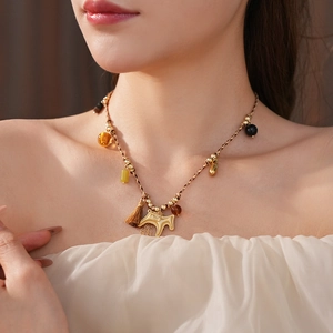 Close-up of woven rope necklace with amber beads and a golden pony pendant on a model