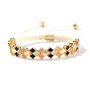 Elegant gold clover bracelet with black enamel, cubic zirconia, and white woven strap