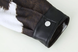 Macro detail of animal print fabric with black leather cuffs and silver metal snaps