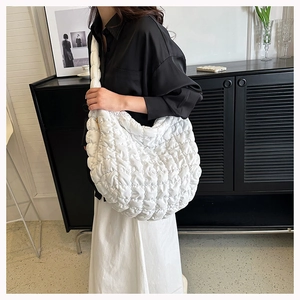 Close-up of white quilted cloud tote bag made of nylon fabric worn on shoulder