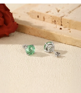 Macro shot of Paraiba green round-cut gemstone earrings in silver four-prong setting
