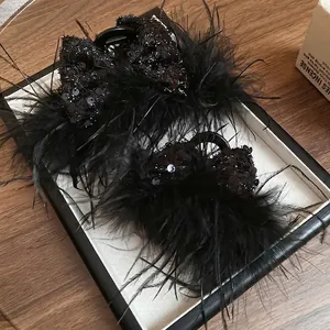 Elegant black feather hair claw set with sequins on white decorative plate