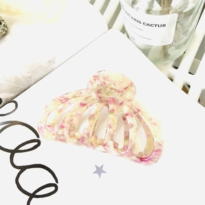 Détail d'une pince à cheveux en acétate marbré rose et jaune au design évidé