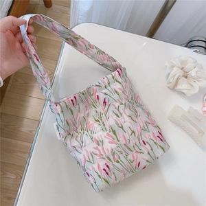 Detail of tulip floral embroidery and fabric texture on a mini tote bag with side label