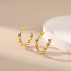 Detail of twisted two-tone C-shape earrings in gold and silver finish with metallic texture