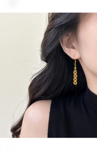 Detail of long gold tassel earring with chain design on model to show the drape length