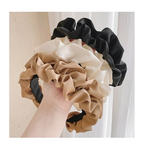 Détail de serre-têtes en satin plissé noir, beige et café avec finition brillante