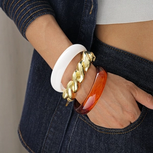Detail view of fashion trio set featuring golden twisted metal and resin bangles