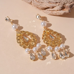 Detailed macro of gold drop earrings featuring intricate woven metal, pearls and crystals