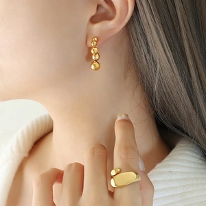 Minimalist gold ball drop earrings and irregular organic open ring set on a female model
