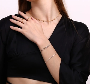 Close-up of 18K gold daisy pendant necklace with layered rings and bracelets on model