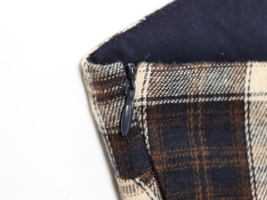 Macro shot of dark blue invisible zipper on brown and beige plaid fabric detailing