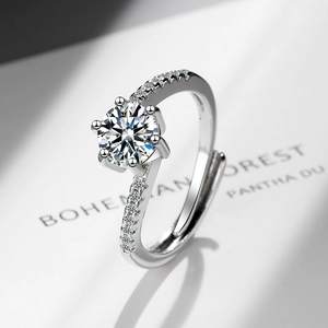 Elegant six-prong round zircon silver ring with side stones on a minimalist book