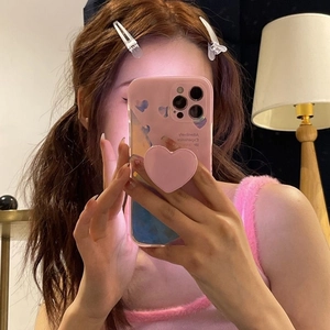 Pink heart-shaped Griptok phone socket grip on a gradient pink case with heart patterns