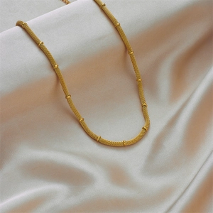 Golden mesh woven necklace with bead accents on elegant light gray silk background