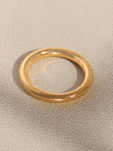 Detailed view of a smooth 18K gold-plated stainless steel band on soft beige velvet fabric