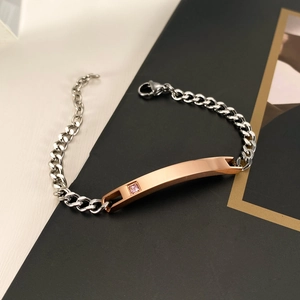 Silver Cuban link bracelet with rose gold plate and pink gem on black magazine