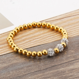 Detail of beaded stretch bracelet with gold steel beads and three sparkling crystal charms