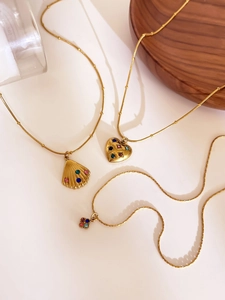 Detailed view of gold stainless steel necklaces with shell, heart, and clover pendants