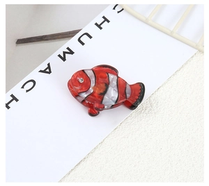 Detailed close-up of a clownfish shaped acetate hair clip with orange stripes and a rhinestone eye