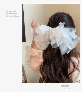 Detail of white mesh floral hair clip with 3D fabric flowers and faux pearls