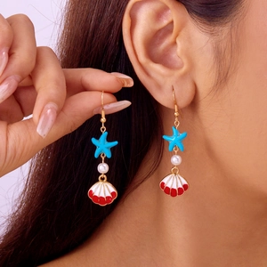 Marine style shell and starfish drop earrings with pearls on a model ear