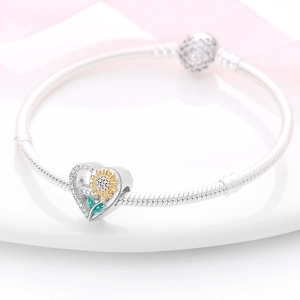 Detalle de pulsera de plata tipo serpiente con dije de corazón girasol y cierre de circonitas