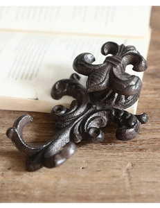 Macro detail of rustic cast iron fleur-de-lis hook on antique wood and book background