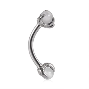 Macro detail of dragon claw curved barbell piercing with white pearl-like beads