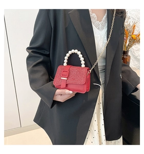 Detail of red sequin mini bag featuring large pearl handle and gold chain strap