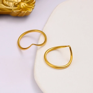 Detailed view of two polished gold V-shaped titanium rings on a white ceramic tray