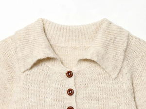Detail of cream knit cardigan featuring classic collar and dark brown buttons