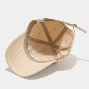 Detail of adjustable metal buckle and 100% cotton inner stitching on beige baseball cap