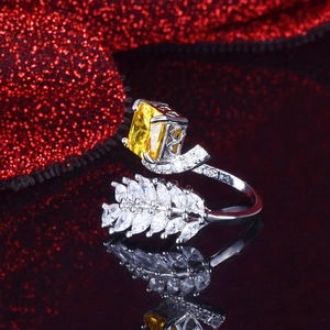 Macro shot of silver ring featuring radiant yellow gemstone and marquise diamond leaves