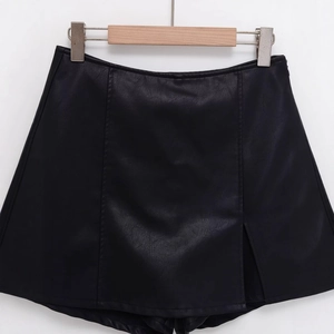 Black faux leather skorts with asymmetric slit design and fine leather grain texture